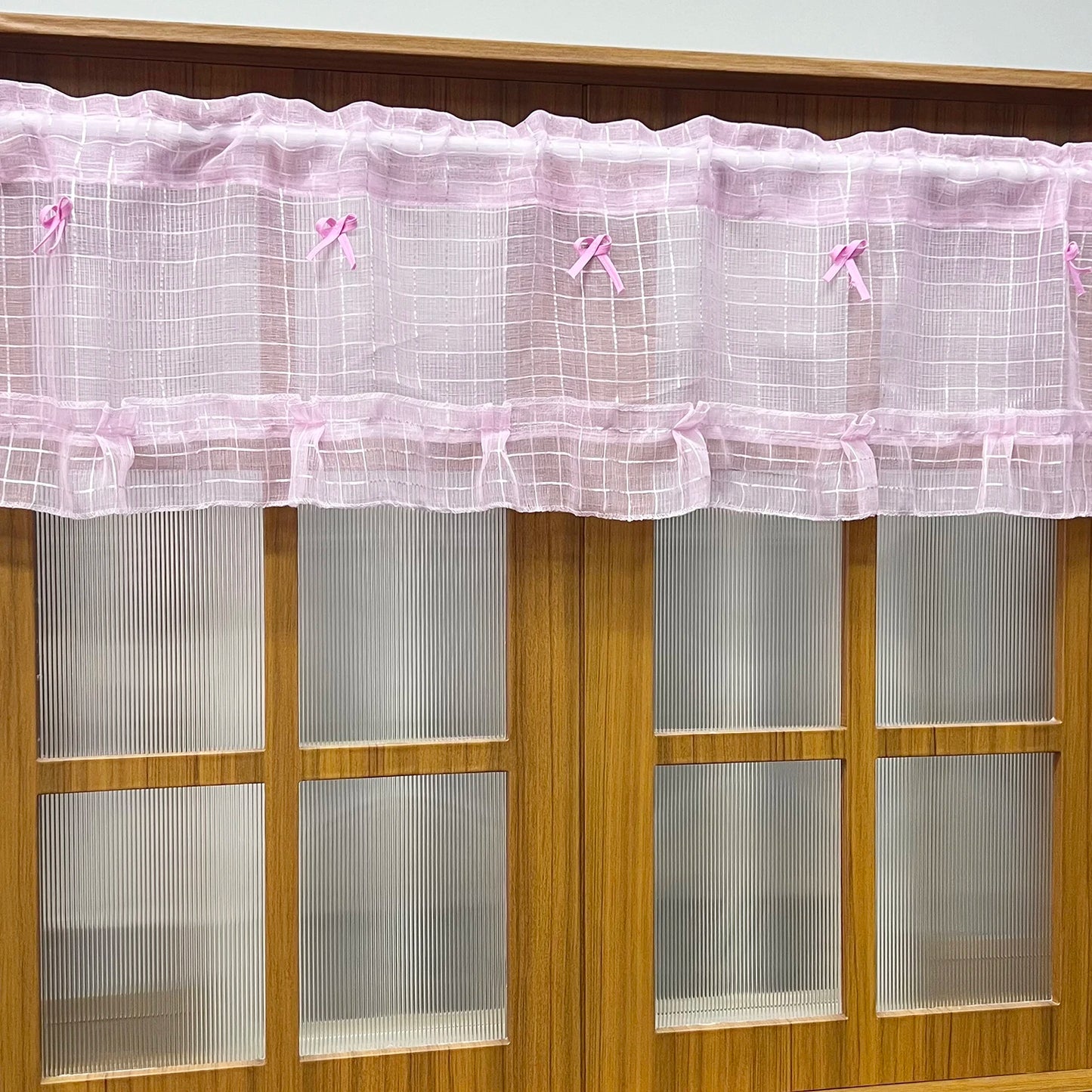 Short curtains made of pink checkered tulle and sheer voile for kitchen cabinets, doors, and windows.