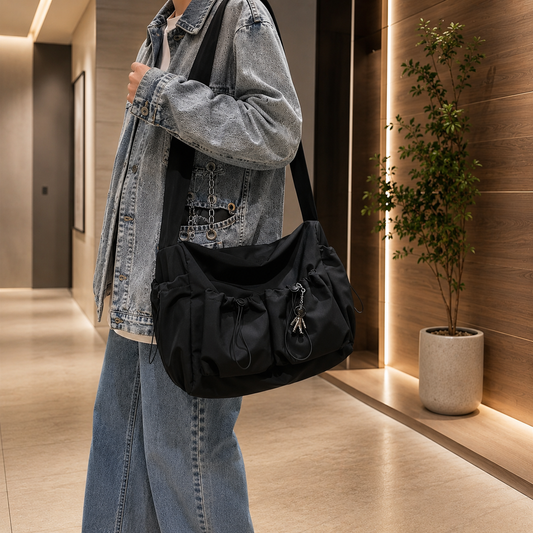 Spacious crossbody bag with a drawstring detail and a charm, featuring a zipper closure