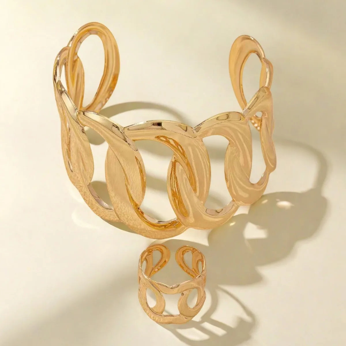 Bracelet and ring set with a geometric design of intertwined and sinuous links, with an adjustable opening